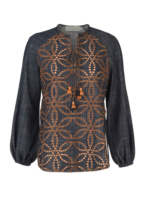 A dark blue long-sleeved Vigolene Blouse Chambray Embroidery featuring an intricate geometric pattern in orange. The high-fashion sleeves add an elegant touch, while a tie at the neckline with tassels completes this chic look.