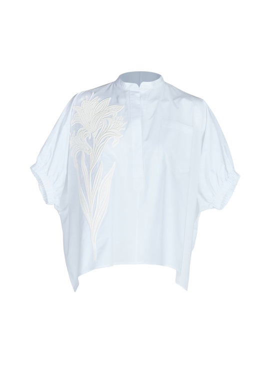 A Susanne Blouse White with embroidered flowers and lace detailing on the cap sleeves.