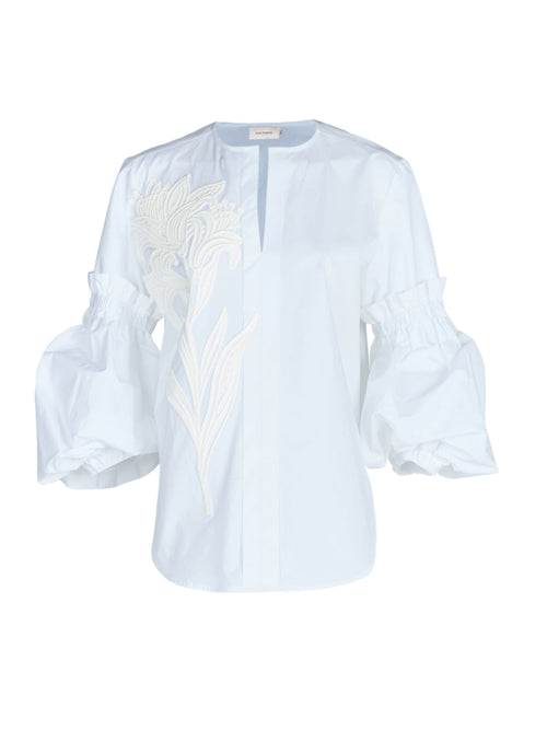 A Wenda blouse white with floral applique on the sleeves.