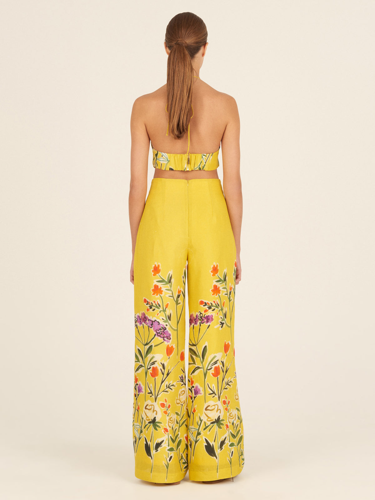 A Bruna Top Golden Wallflowers with a vibrant floral pattern in yellow, orange, and green on a white background features a cropped silhouette.