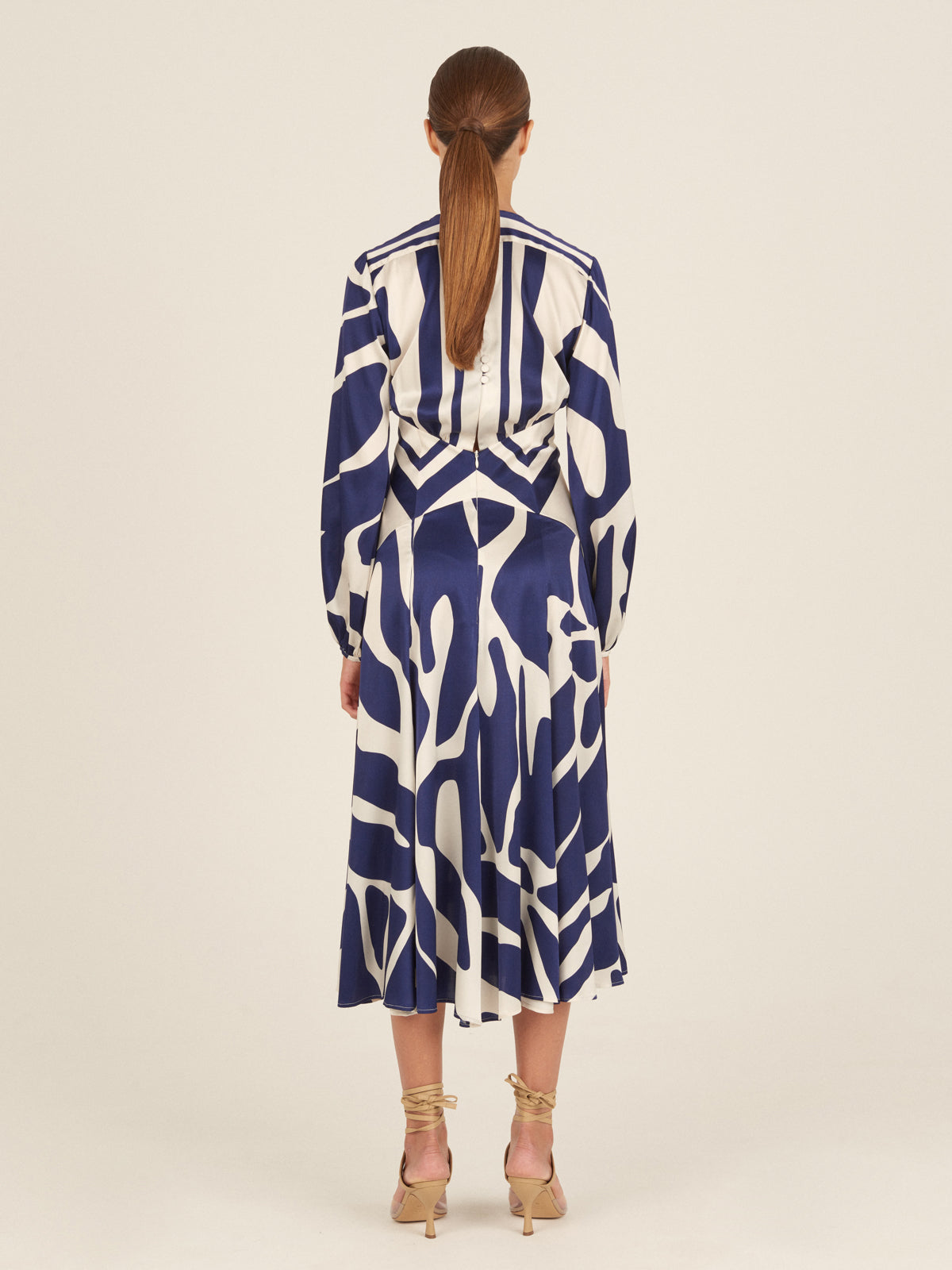 The Kathryn Dress Navy White Mosaic is a knee-length piece with a deep V-neckline and long sleeves, featuring a bold blue and white mosaic print that captures the essence of Spring 2023.