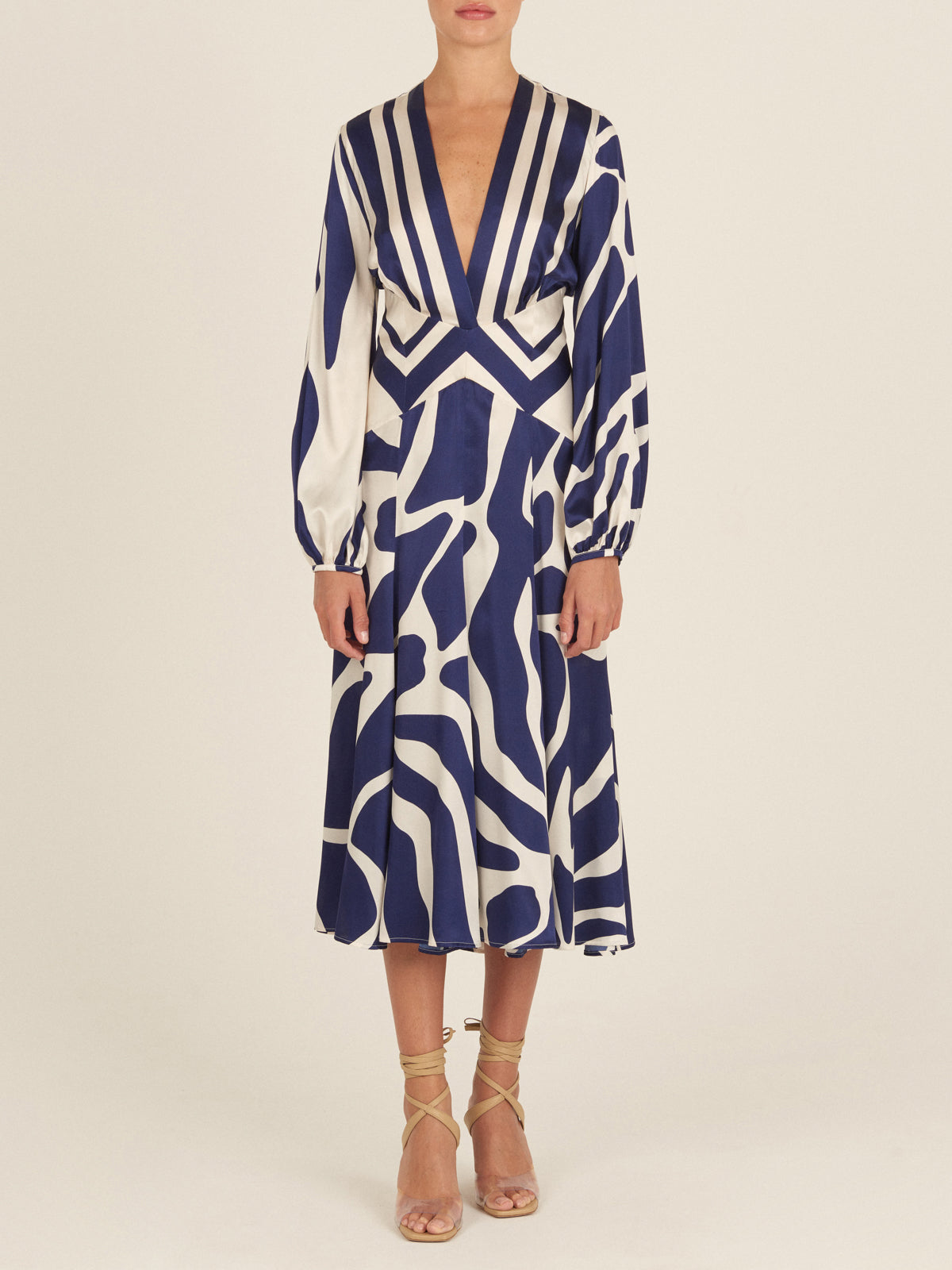 The Kathryn Dress Navy White Mosaic is a knee-length piece with a deep V-neckline and long sleeves, featuring a bold blue and white mosaic print that captures the essence of Spring 2023.