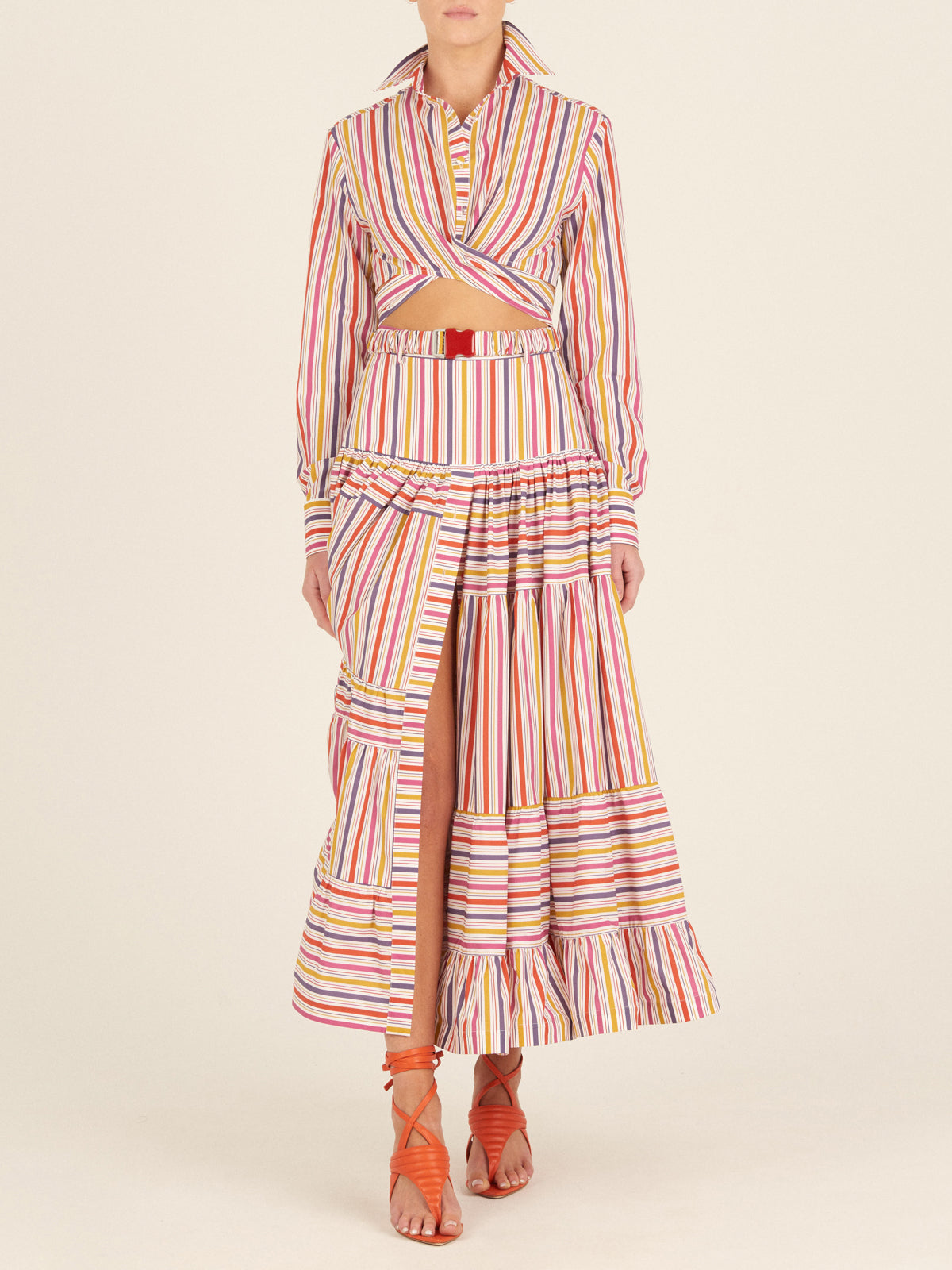 Marcel Blouse Golden Magenta Stripes in cropped style, featuring a twist front detail and multicolored gold magenta striped fabric, complete with buttoned cuffs.