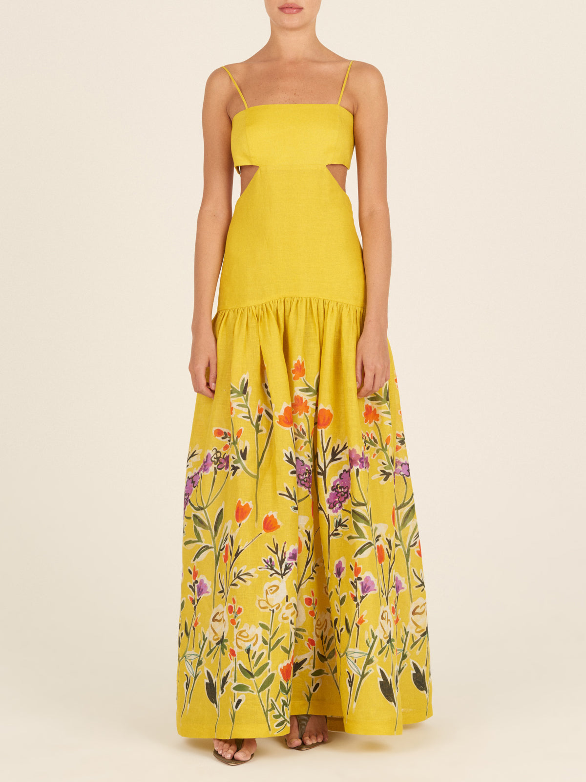 The Shannon Dress Golden Wallflowers is a yellow sleeveless maxi dress with thin straps, boasting a fitted bodice and a flared skirt adorned with colorful floral embroidery near the hem, making it perfect as a vacation maxi dress.