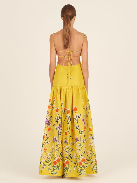 The Shannon Dress Golden Wallflowers is a yellow sleeveless maxi dress with thin straps, boasting a fitted bodice and a flared skirt adorned with colorful floral embroidery near the hem, making it perfect as a vacation maxi dress.