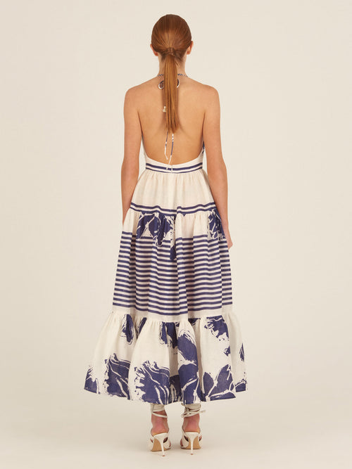 The Valerie Dress Azure Floral Stripes is a charming addition to your Spring 2023 wardrobe, featuring a sleeveless, halter-neck design with azure floral stripes and blue floral prints on the skirt and hemline.