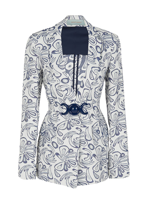 The Cuneo Jacket Swirls is a versatile piece featuring a white and blue patterned design with long sleeves. It showcases a dark blue rectangular panel on the chest and includes a decorative belt with a circular buckle at the waist, making it both stylish and adaptable for various occasions.