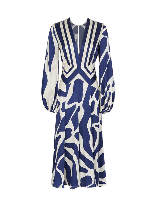 The Kathryn Dress Navy White Mosaic is a knee-length piece with a deep V-neckline and long sleeves, featuring a bold blue and white mosaic print that captures the essence of Spring 2023.